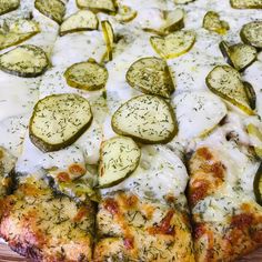 a pizza covered in cheese and cucumbers on a cutting board