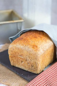 a loaf of bread sitting on top of a black plate next to a red and white checkered napkin