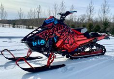 a red and black snowmobile parked in the snow