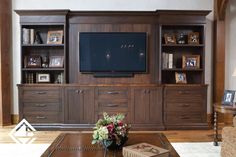 a living room with wooden furniture and a flat screen tv mounted to the side of a wall