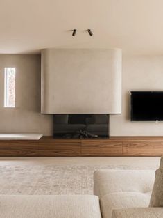 a modern living room with white furniture and a flat screen tv mounted on the wall