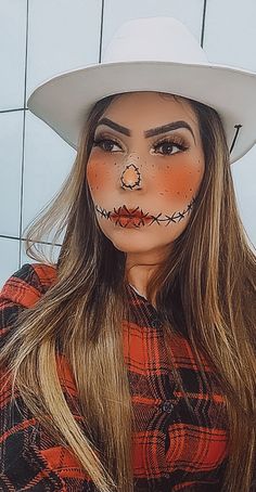 a woman wearing a white cowboy hat and orange makeup