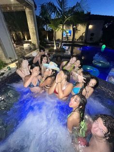 a group of people in a pool at night with water spraying from their mouths and hands