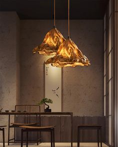 two wooden chairs are sitting in front of a table and some lights hanging from the ceiling