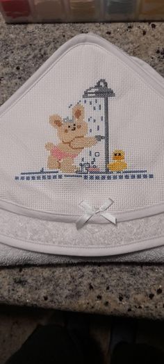 a cross - stitch baby bib with a teddy bear and ducky on it