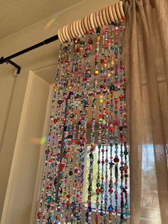 a curtain with beads hanging from it's side in front of a window sill