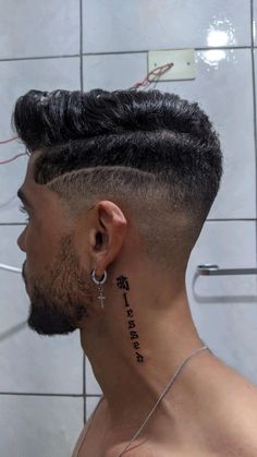 a man with a cross tattoo on his neck is looking at the shower stall wall