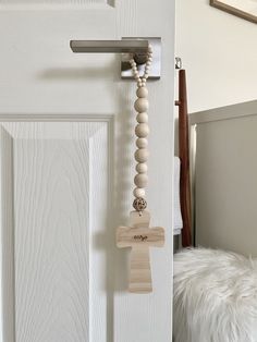 a wooden cross hanging on a door handle with bead necklaces attached to it