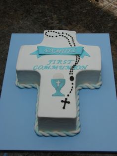 a cake shaped like a cross with a blue ribbon around it that says first coming soon