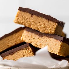 three pieces of peanut butter bars stacked on top of each other in a white bowl