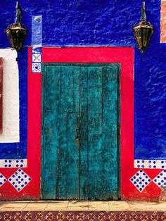 a blue and red building with an open wooden door in front of the entrance to it