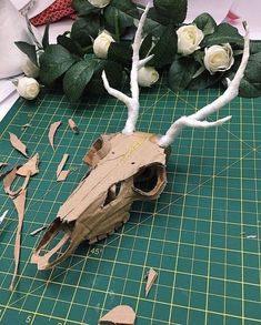 an animal skull is made out of cardboard and flowers are on the table next to it