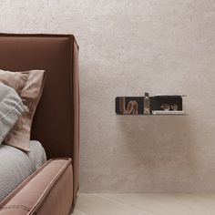 a bed with two pillows on top of it next to a wall mounted book shelf