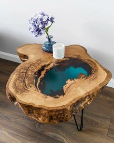 a table made out of a tree trunk with blue water in the center and flowers on top