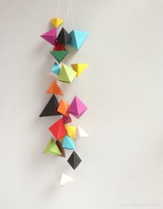 an origami mobile is hanging on the wall, with several different colored triangles