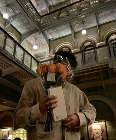 a man holding flowers and a card in front of his face while wearing a mask