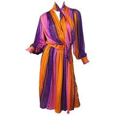 Pretty 1970s orange, pink and purple slinky jersey wrap dress with attached neck scarf ! Features vibrant colors with an Aztec like print throughout. Colorful rhinestone buttons at each French cuff. Wrap style that has interior adjustable velcro closure. Great for evening or day. Pair with flats, wedges or sandals for day, and heels for evening. In great condition Made in USA Approximately Size Medium Measurements: 34-44 inch bust ( stretch and wrap style ) 26-28 inch waist 44-48 inch hips 47 inches from top back shoulder seam to hem 70s Scarf, Peter Pan Dress, Long Flower Dress, Pink Chiffon Dress, Pink Orange Purple, Vintage Dress 60s, Jersey Wrap Dress, Linen Tunic Dress, Sheer Gown