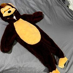 a stuffed monkey laying on top of a bed next to a gray sheet covered wall