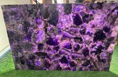 a large purple marble slab sitting on top of green grass