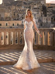 a woman in a wedding dress is standing on steps near an old cityscape