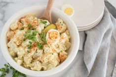 a white bowl filled with potato salad next to an egg