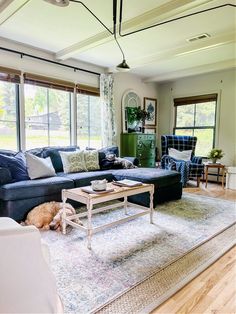 a living room with blue couches and white rugs on the hardwood flooring