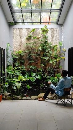 a person sitting on a chair in a room with plants