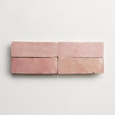 three pink bricks on a white surface