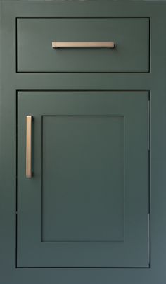 a green cabinet door with brass handles and knobs on the bottom, against a blue wall