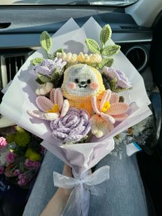 a stuffed animal sitting on top of a bouquet of flowers in the back seat of a car