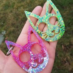 there are two handmade masks in the palm of someone's hand, one is pink and one is green