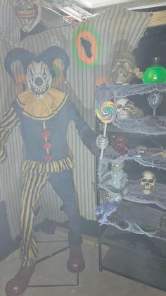 a man dressed as a clown standing in front of a shelf filled with halloween items