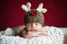 a newborn baby wearing a knitted reindeer hat