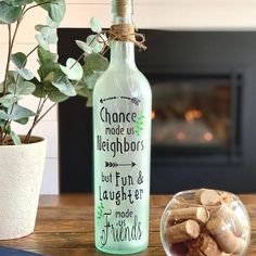 a glass bottle filled with wine next to a potted plant on a wooden table