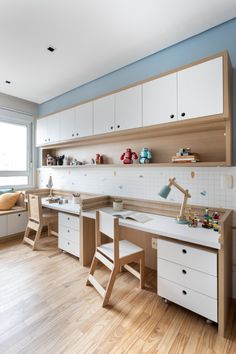 a room with wooden floors, white cabinets and shelves filled with toys on top of them