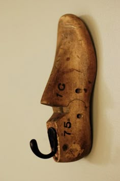 a wooden mask mounted to the side of a wall with an umbrella hook in it