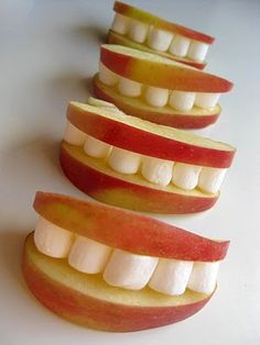 four slices of apple with white teeth and one cut in half to look like an apple