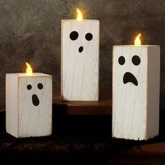 three white candles with faces painted on them