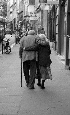 an old couple walking down the street with their back to each other and holding hands