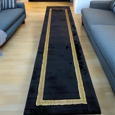 a long black rug with gold trim on the floor in a living room next to couches