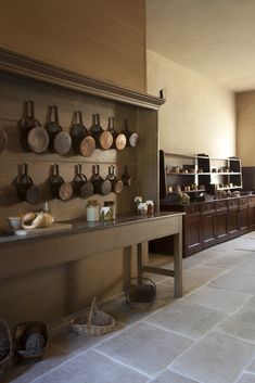 a kitchen with pots and pans on the wall next to a table in front of it