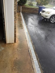 a white car parked in front of a building on a rainy day with rain coming down