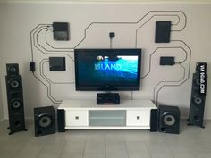 a flat screen tv sitting on top of a white entertainment center in front of speakers