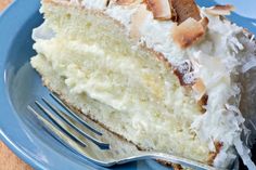 a slice of coconut cake on a blue plate with a fork in front of it