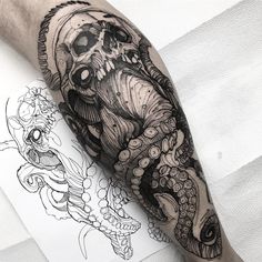 a man's arm with an octopus and skull tattoo design on the left forearm