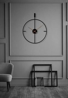 a chair sitting in front of a clock on the wall next to a small table