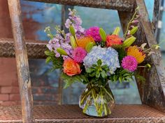 a vase filled with colorful flowers sitting on top of a wooden chair