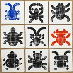 four square tiles with black and red designs on them, all in different shapes to resemble crabs