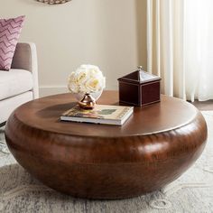 a living room with a round coffee table and white flowers on top of the ottoman