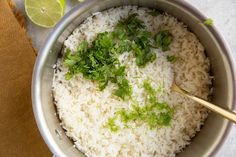 rice and cilantro in a pot with limes next to it on a table